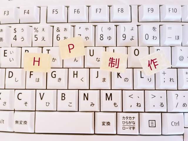 キーボードの上にあるHP制作と書かれた積み木